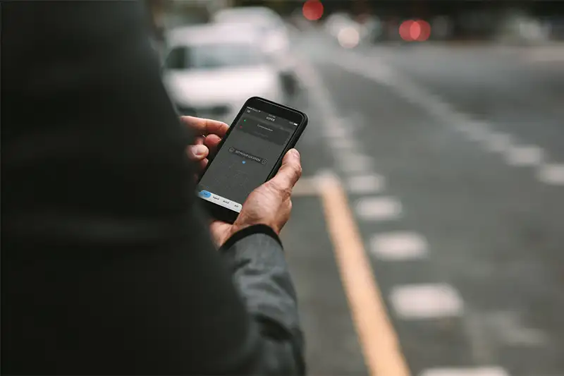 Close up of person holding phone and using rideshare app
