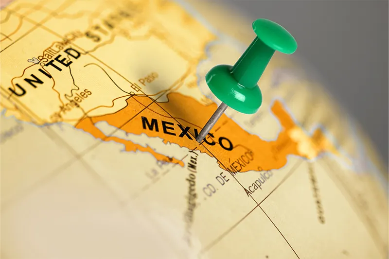 Green pushpin on Mexico on globe