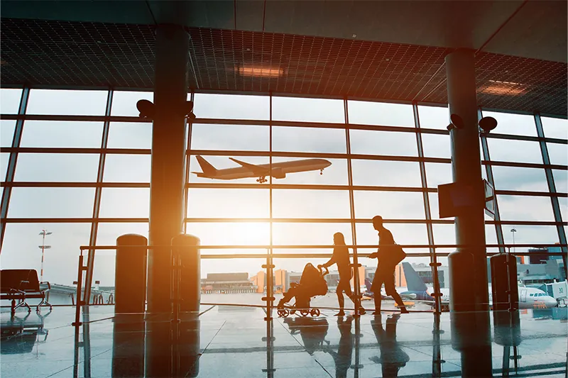 People walking through airport terminal early in the morning, silhouetted against the window 