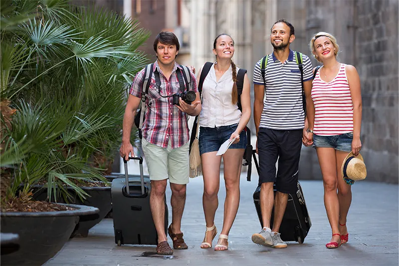 Four casually dressed tourists towing luggage