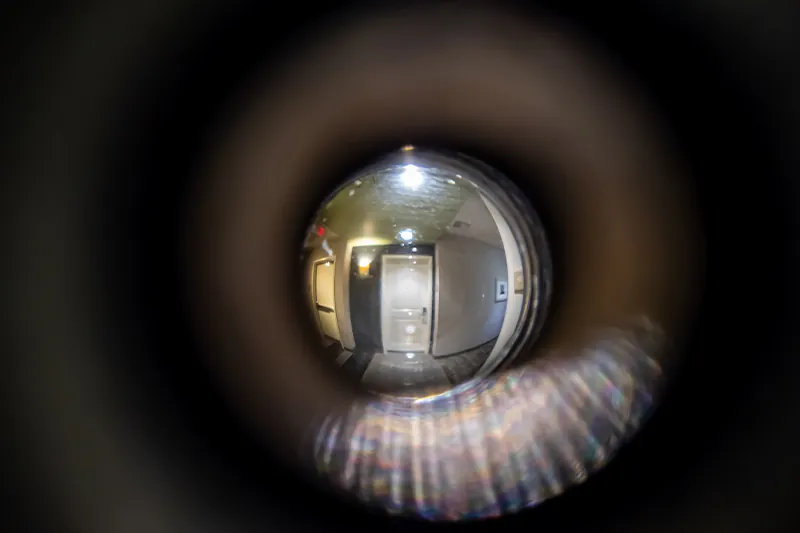 Point of view looking through a peephole into a hotel hallway