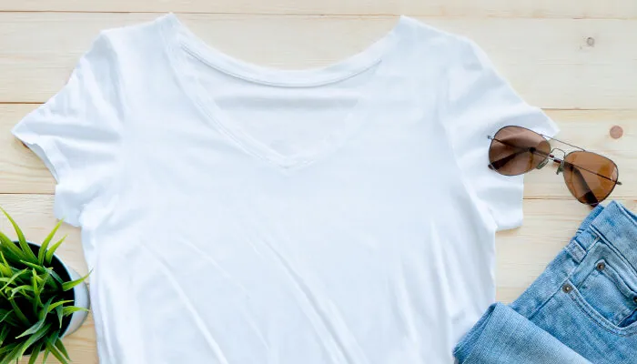 Flaty lay of white t-shirt, a plant, jeans, and sunglasses